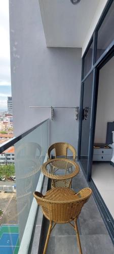 two chairs and a glass table on a balcony at Bian's Cozy Suite in Kota Kinabalu