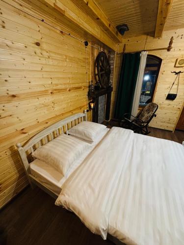 a bed in a room with a wooden wall at Alashkert Guesthouse ,Ալաշկերտ Հյուրատուն in Gyumri
