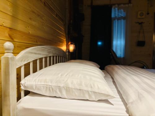 two white pillows on a bed with a wooden wall at Alashkert Guesthouse ,Ալաշկերտ Հյուրատուն in Gyumri