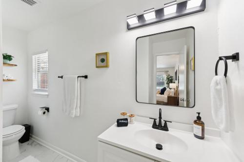 a white bathroom with a sink and a mirror at Boho Bungalow near DFW Airport in Farmers Branch