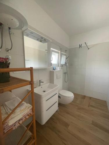 a white bathroom with a toilet and a sink at Apartmani Stellar in Malinska