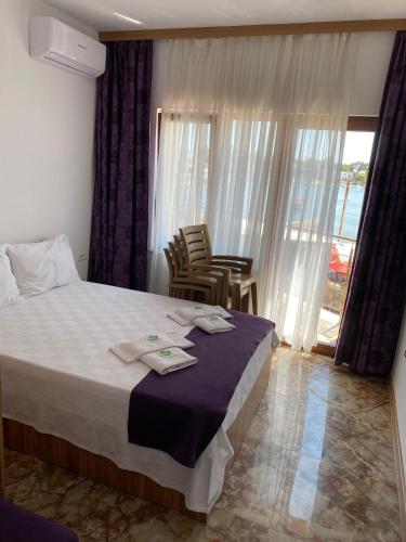 a bedroom with a bed and two chairs and a window at Hotel Prestige Beach in Costinesti