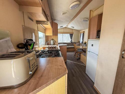 a kitchen with a stove and a counter top at Lovely Caravan At Valley Farm Holiday Park, Sleeps 8 Ref 46127V in Great Clacton