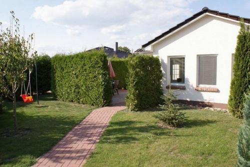 a garden with a white house and a brick path at Sonnenschein - ABC237 in Zierow
