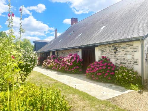 a house with pink flowers on the side of it at Le Logis du pic vert in Saint-Mathurin