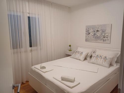 a white bed in a white room with a window at Apartmani Šperanda Pisak in Pisak