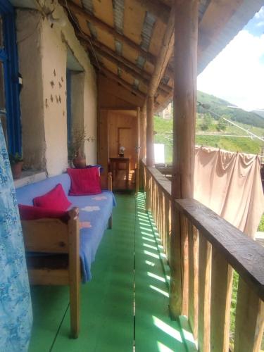 a porch of a house with a blue couch and red pillows at Hotel Family Bachi in Adishi