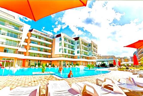a resort with a swimming pool with chairs and umbrellas at Apartcomplex Grand Kamelia Sunny Beach in Sunny Beach