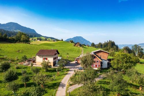 a village in a green field with mountains in the background at B&B Hof Grosschreie in Hasle
