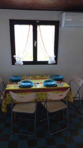 a table with two chairs and a yellow table and two windows at Camping Alpino - Nature Village in Malcesine