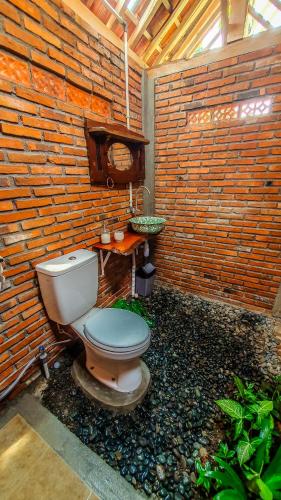 a bathroom with a toilet in a brick wall at Rumah Gaharu - Wetan 