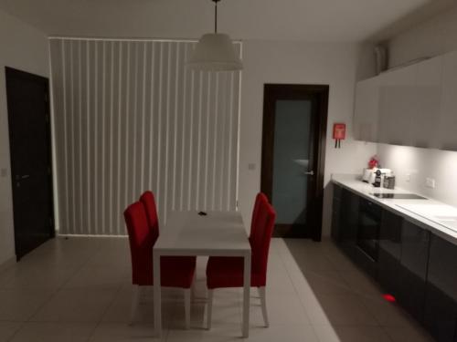a kitchen with a white table and red chairs at Mercury Gardens in St Julian's