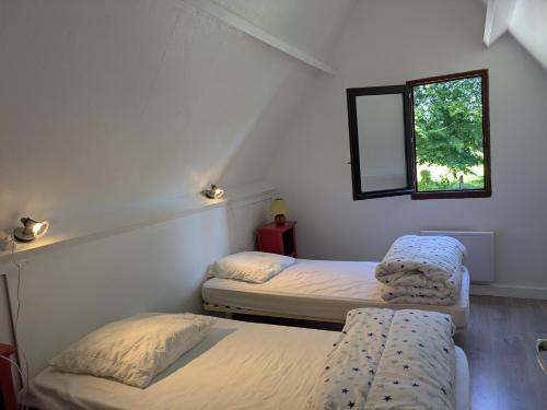 two twin beds in a room with a window at Gîte à la ferme - proche Etretat in Goderville