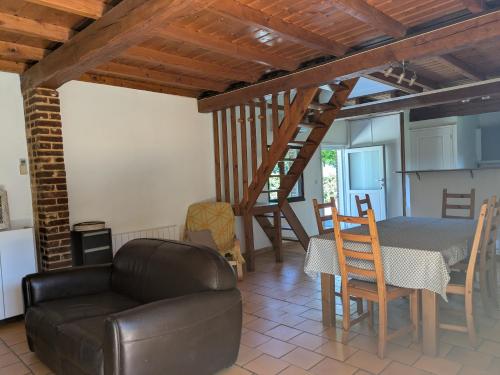 a living room with a table and a couch and a staircase at Gîte à la ferme - proche Etretat in Goderville