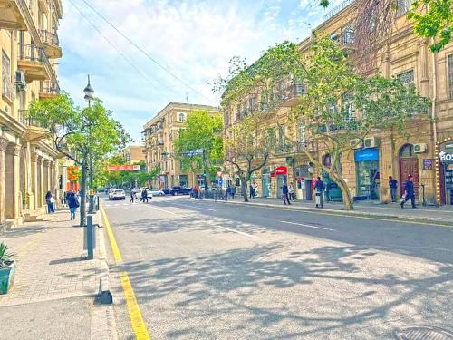 a city street with buildings and people walking down the street at Liberta Baku City Center in Baku
