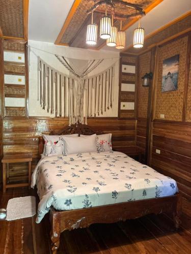 a bedroom with a bed in a room with wooden walls at BING-VICE Tourist Inn in San Vicente