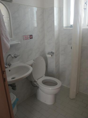 a white bathroom with a toilet and a sink at Castle View Apartments in Haraki