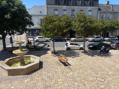 a park with a fountain and a bench and cars at Plein centre in Malesherbes
