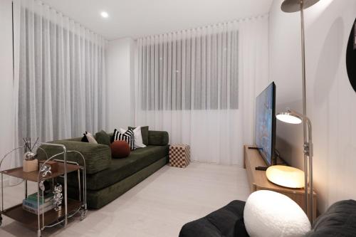 a living room with a green couch and a tv at 'Vinyl' 1-BR Apt in the heart of Burwood with study n free parking in Sydney