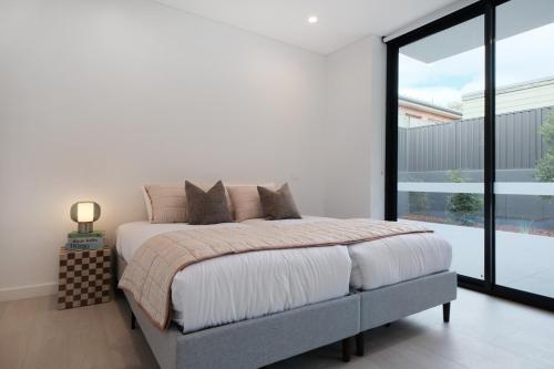 a bedroom with a bed and a large window at 'Vinyl' 1-BR Apt in the heart of Burwood with study n free parking in Sydney