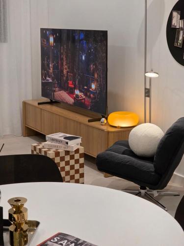 a living room with a tv and two chairs and a table at 'Vinyl' 1-BR Apt in the heart of Burwood with study n free parking in Sydney