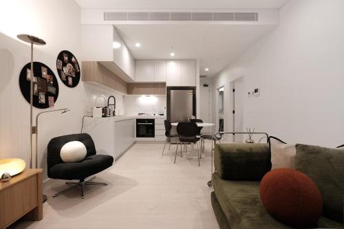 a living room with a couch and chairs and a kitchen at 'Vinyl' 1-BR Apt in the heart of Burwood with study n free parking in Sydney