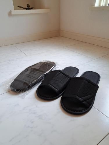 a pair of black slippers sitting on a white floor at 民泊リリリゾート in Ichihara