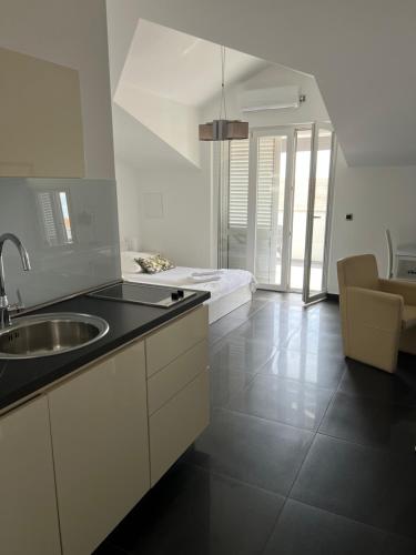 a white kitchen with a sink and a bed at Apartment Vodice - Lovric in Vodice