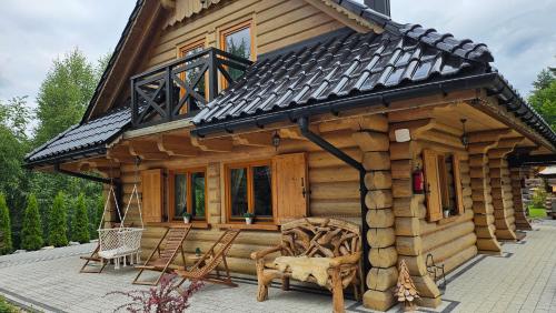 a small log cabin with a porch and chairs at Osada Kuboski Dom z Bali Leśny Zakątek in Kamesznica