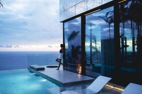 a woman walking on the balcony of a building at Saudade Residence - Ultra Luxury Futuristic Ocean Zen Retreat in Ribeira Brava