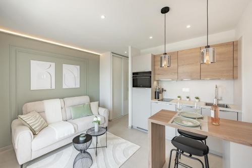 un salon avec un canapé blanc et une cuisine dans l'établissement BLEU PARADIS - Studio Cosy - Vue Mer & Terrasse Romantique - Parking privé, aux Issambres