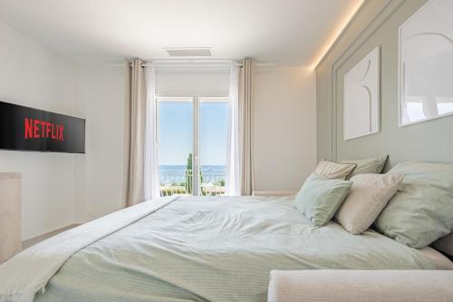 une chambre blanche avec un grand lit avec une fenêtre dans l'établissement BLEU PARADIS - Studio Cosy - Vue Mer & Terrasse Romantique - Parking privé, aux Issambres