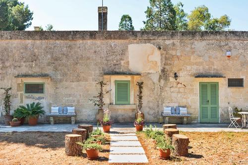a stone building with green doors and benches at Masseria San Nicola dei Baroni di Castiglione in Vignacastrisi