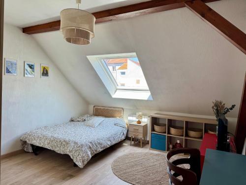 - une chambre mansardée avec un lit et une lucarne dans l'établissement Maison familiale 4P 10 min Strasbourg centre, à Schiltigheim