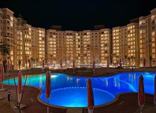 a large building with a large blue swimming pool at night at Aqua View Studio in Dawwār Abū Maḩrūs