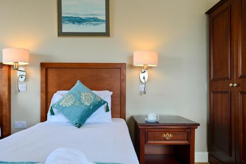 a bedroom with a bed with a blue pillow on it at Lawlors Hotel Dungarvan in Dungarvan