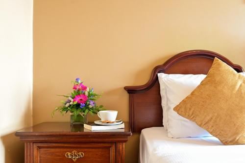 a bed with a table with a vase of flowers on it at Lawlors Hotel Dungarvan in Dungarvan