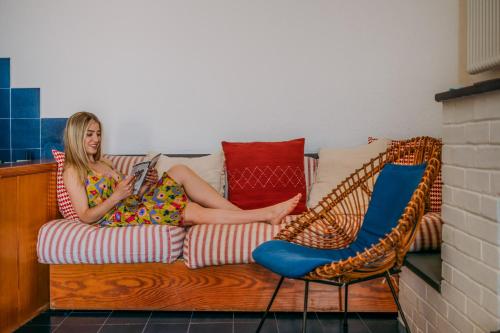 a woman sitting on a couch reading a book at Il Baluardo Sea View Apartment on the Cliff in Manarola