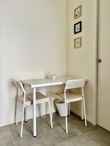 - une table et des chaises blanches dans la chambre dans l'établissement Joli studio récent sur jardin, très calme, à Colombes