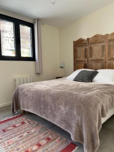 une chambre avec un grand lit avec une tête de lit en bois dans l'établissement Joli studio récent sur jardin, très calme, à Colombes