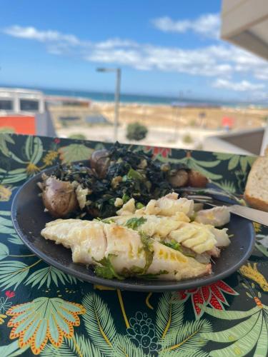 a plate of food on a table with a view of the beach at Lisbon Beach Flat- Costa Caparica in Costa da Caparica