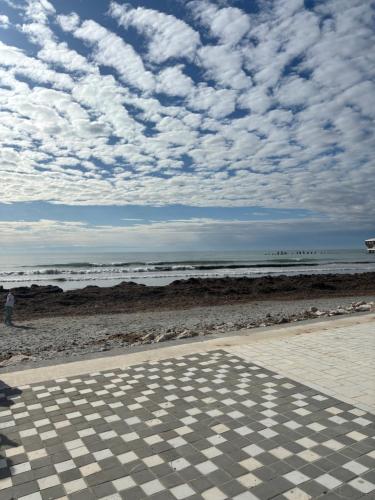a checkered floor on a beach with a cloudy sky at Balcony on the sea in Durrës
