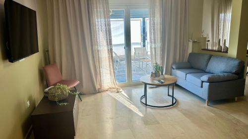 a living room with a blue couch and a table at SeaBreeze Penthouse with Private Parking in Alexandroupoli