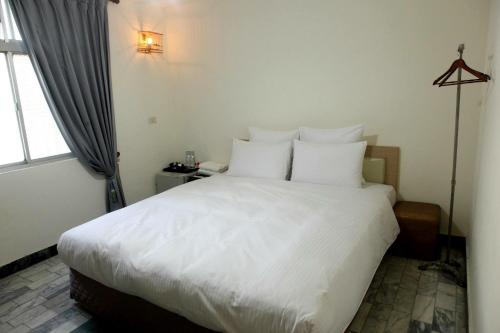 a bedroom with a large bed with white sheets and pillows at 寄居謝 民宿 in Ch'ih-k'an-lou