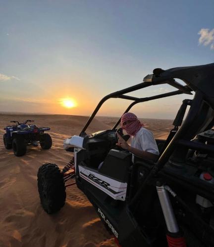 a man sitting in a golf cart in the desert at Sahara Elegance Camp in Merzouga