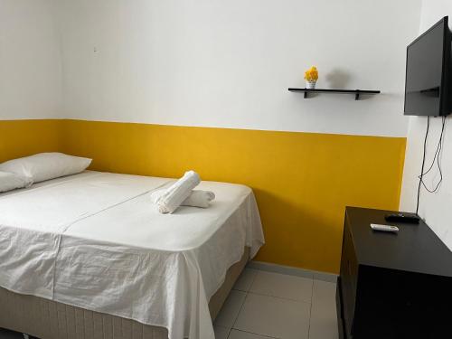 a room with a bed with a yellow wall and a tv at Casa com piscina em Carapibus - Jacumã in Conde