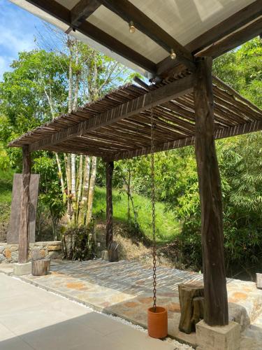 a wooden pergola with a bench and a swing at Hotel Boutique Albania in Otanche