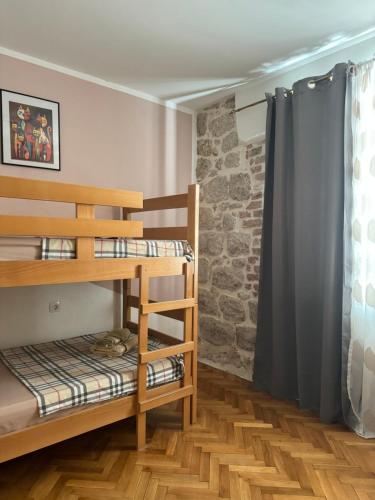 a room with bunk beds and a stone wall at Cozy Little House Kotor in Kotor