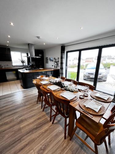 a dining room with a long table and a kitchen at Dreghorn House 5 b-rooms 9 beds 3 toilets 2 showers,1 bath 2 receiption Secure free Parking 233 Wifi in Edinburgh