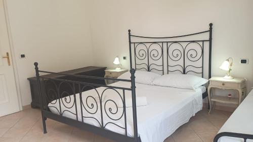 a bedroom with a black metal bed with white sheets at Fratti Central Beach Rooms in Viareggio